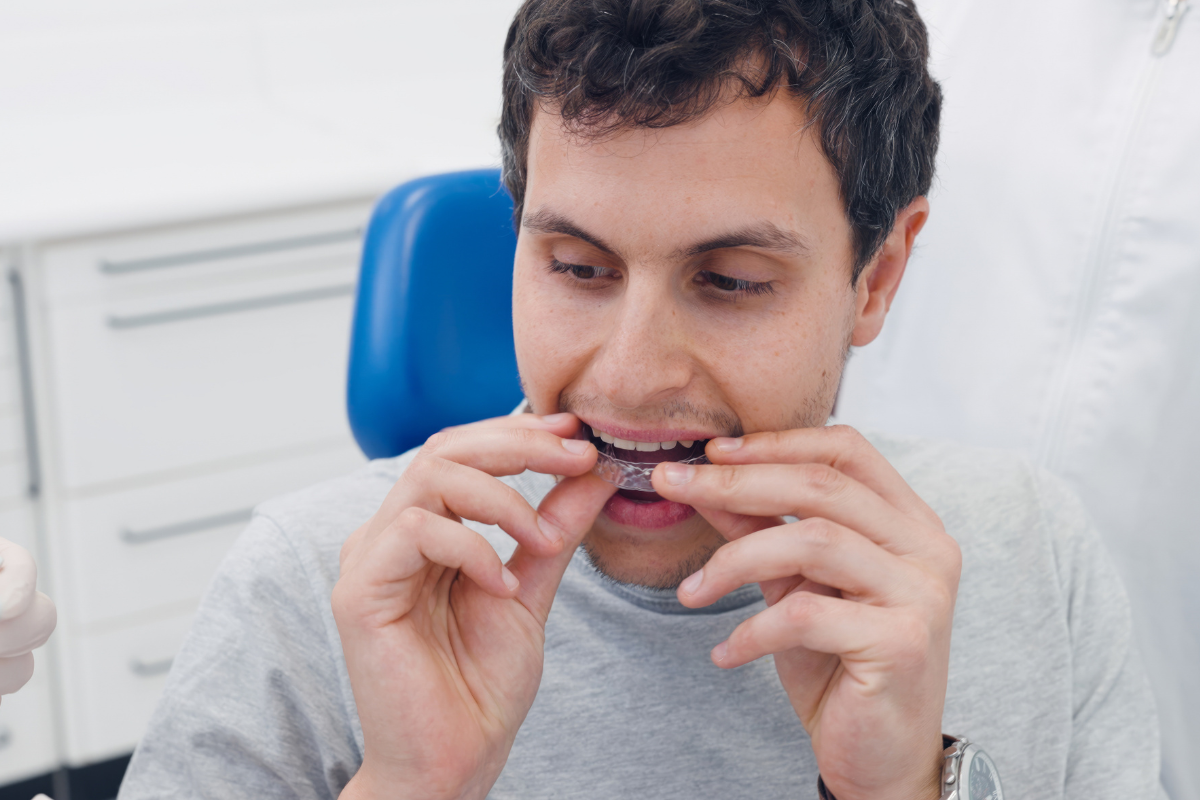 Patient holding clear Vivera retainer to maintain smile after Invisalign treatment at dental office