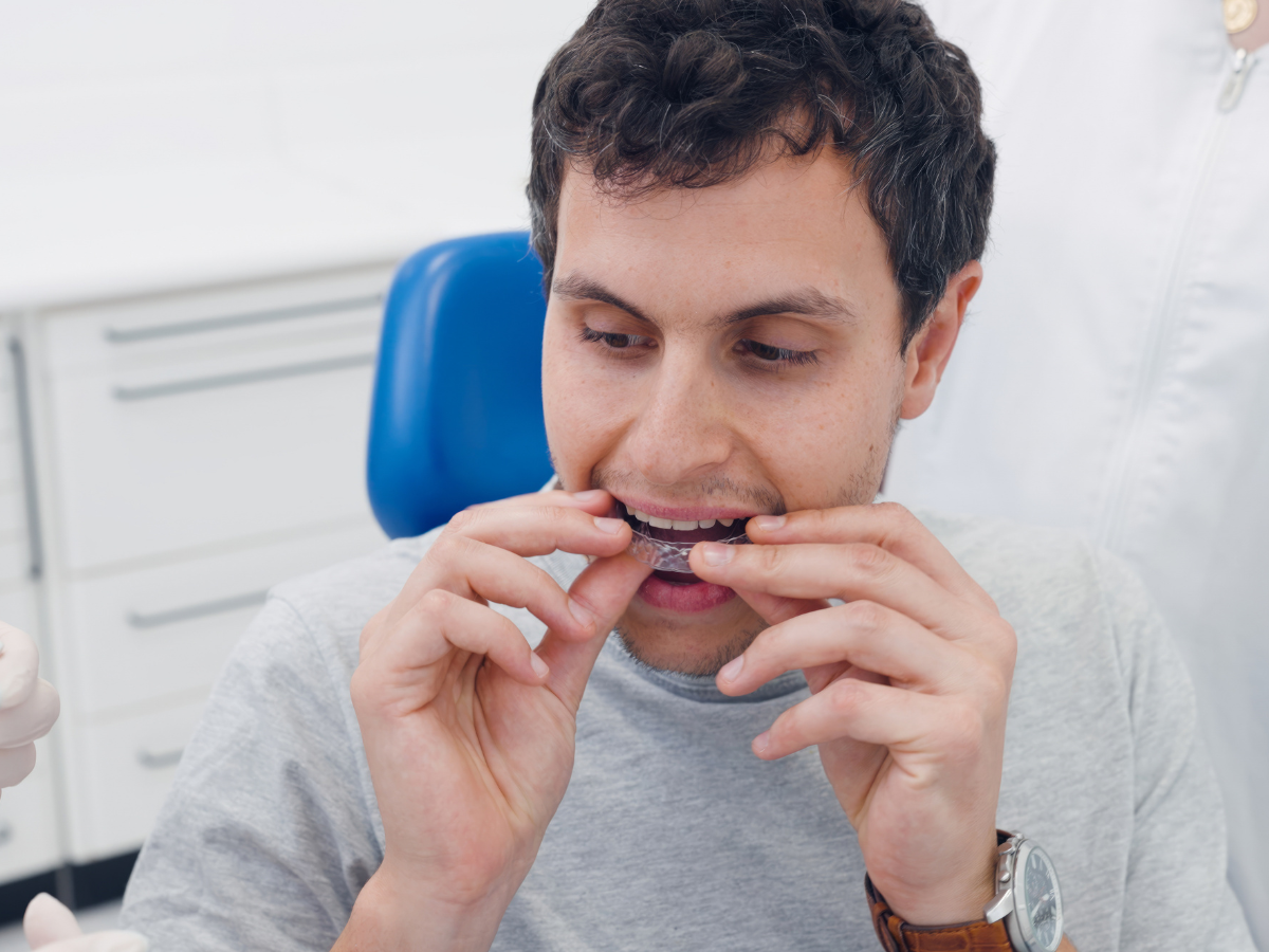 Patient holding clear Vivera retainer to maintain smile after Invisalign treatment at dental office